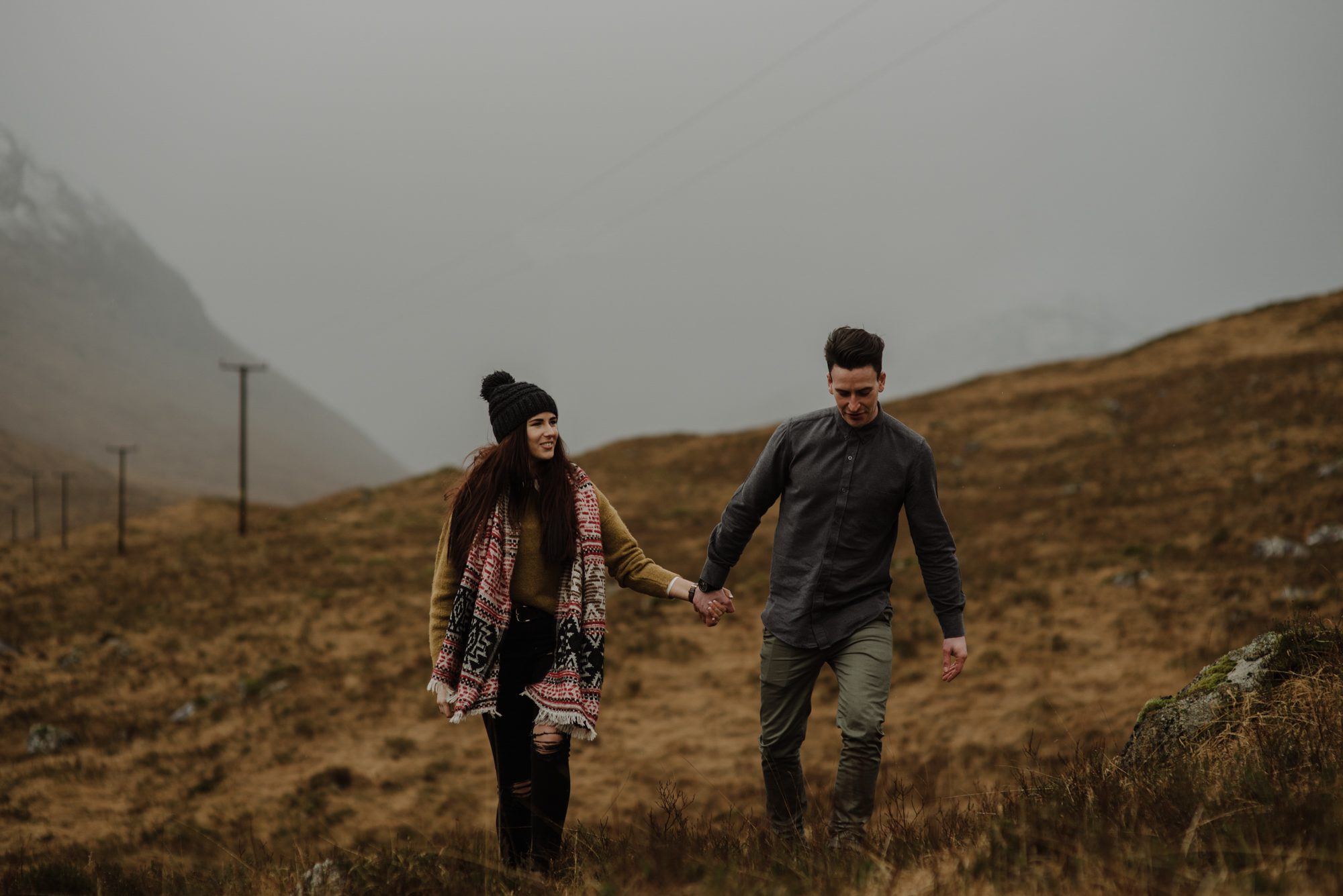 couple walking across heather holding hands in glencoe